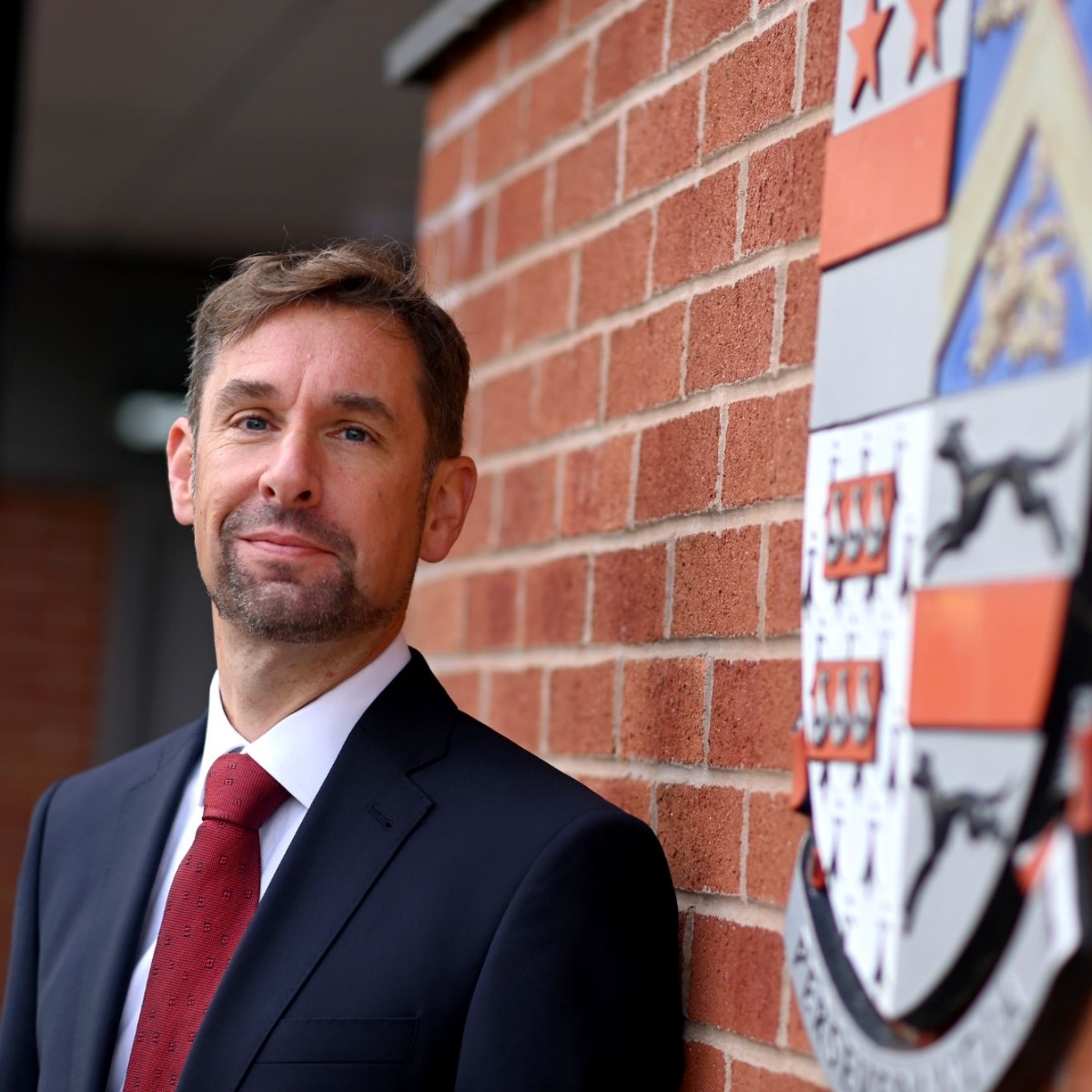 Charles B Fillingham standing by the school shield